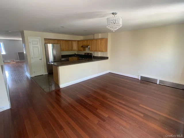 a view of kitchen with empty room and wooden floor