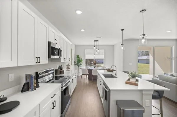 a kitchen with stainless steel appliances kitchen island granite countertop a sink stove and white cabinets with wooden floor