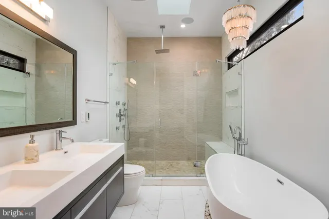 a bathroom with a sink a toilet a mirror and shower