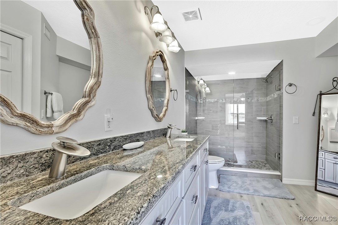 2855 North Rivers Edge Boulevard, Unit 213 Crystal River, FL 34429 - Photo 27 of 62 a bathroom with a granite countertop double vanity sink a mirror and a shower