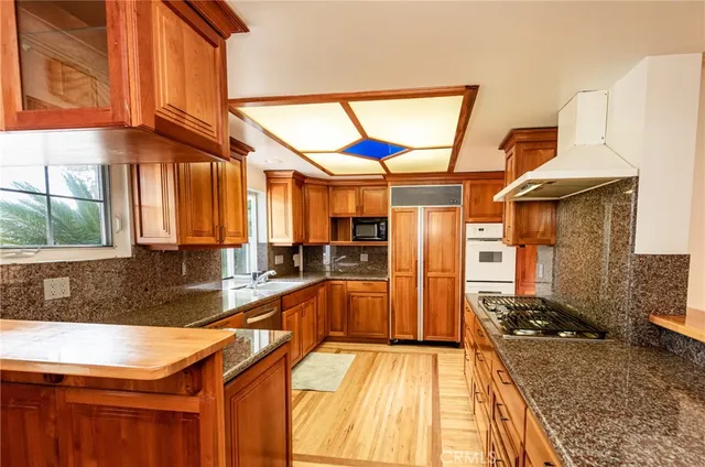 a kitchen with stainless steel appliances granite countertop a sink a stove and a wooden floors