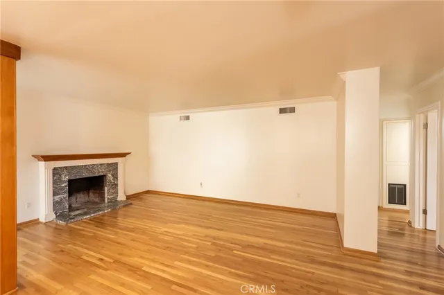 a view of an empty room with wooden floor and a fireplace