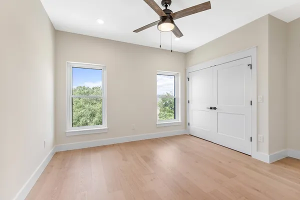 an empty room with windows and fan