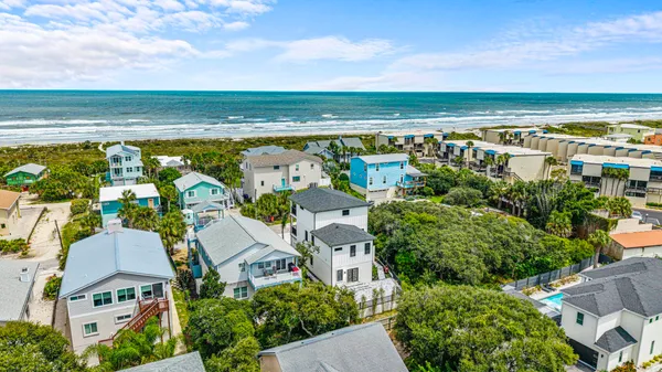 an aerial view of ocean and residential houses with outdoor space