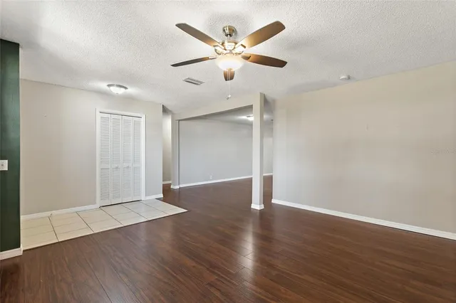 an empty room with wooden floor and ceiling fan
