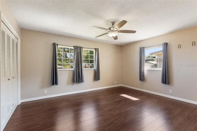 a view of an empty room with a window and wooden floor