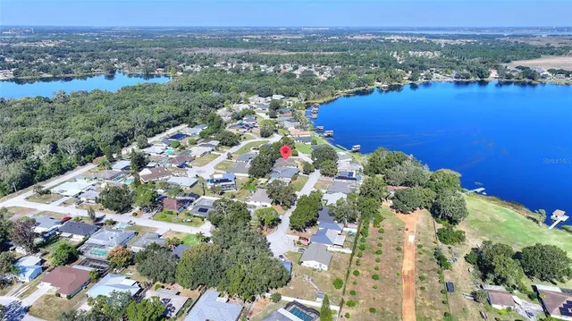 an aerial view of a houses with a yard and lake view