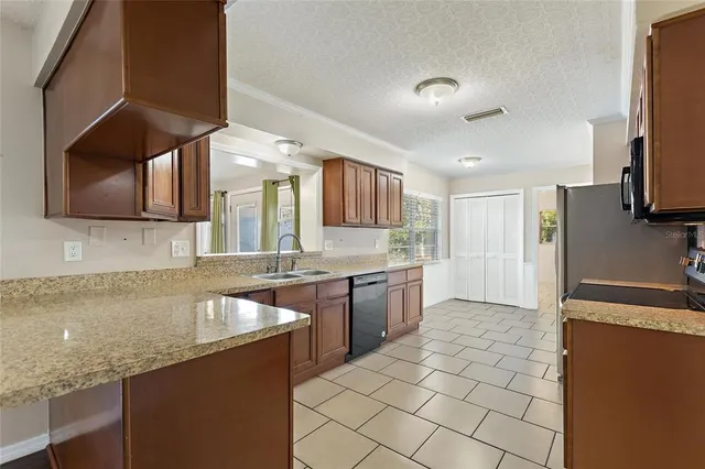 a large kitchen with granite countertop a sink a stove top oven a granite counter space and cabinets