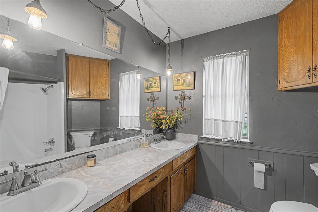 243 County Road 3851 Poolville, TX 76487 - Photo 21 of 34 a bathroom with a granite countertop sink a large mirror a and a window