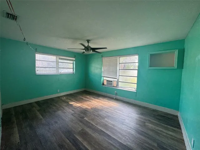 a view of empty room with wooden floor and fan