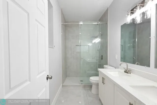 a bathroom with a double vanity sink toilet mirror and shower
