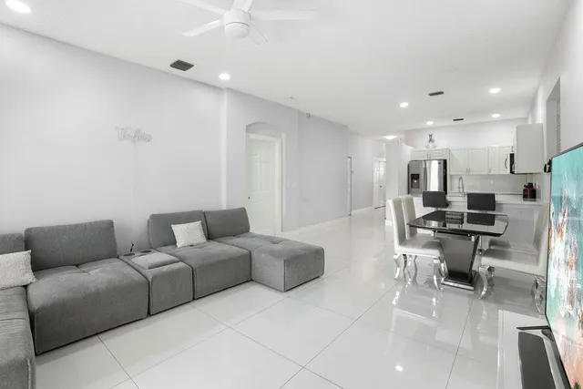 a living room with furniture a kitchen view and a piano