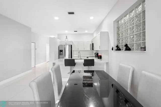 a kitchen with stainless steel appliances a microwave a stove a refrigerator white cabinets and wooden floor