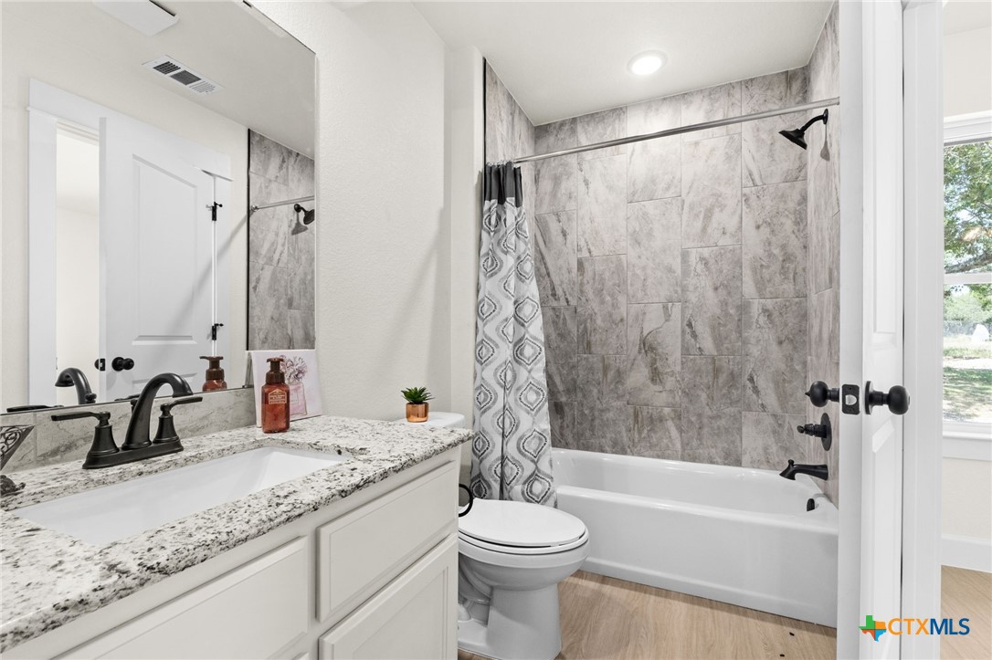 3025 Millhouse Road Copperas Cove, TX 76522 - Photo 27 of 38 a bathroom with a granite countertop sink toilet and shower