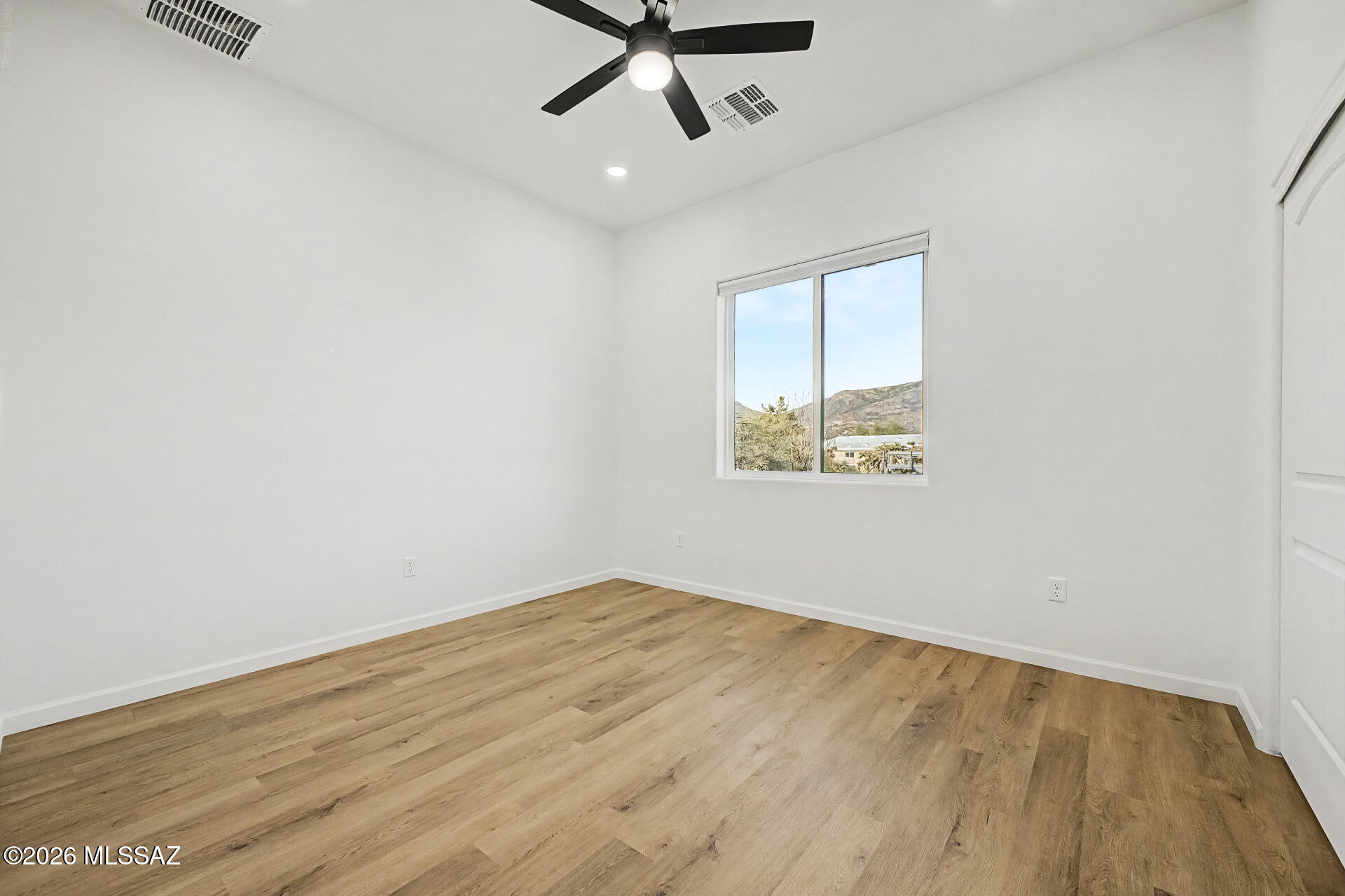 4601 East Magoo Road Tucson, AZ 85739 - Photo 18 of 38 an empty room with wooden floor ceiling fan and windows