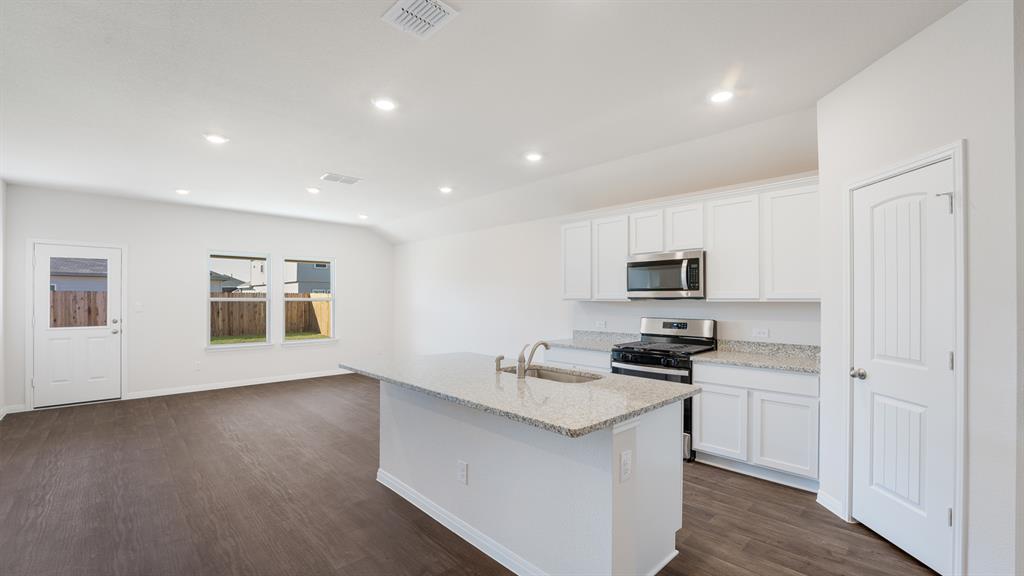 14021 Feinstein Street Manor, TX 78653 - Photo 4 of 25 A well-lit kitchen with granite counters and stainless steel appliances awaits culinary adventures.