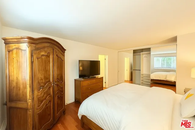 a bedroom with a bed and a flat tv screen on dresser