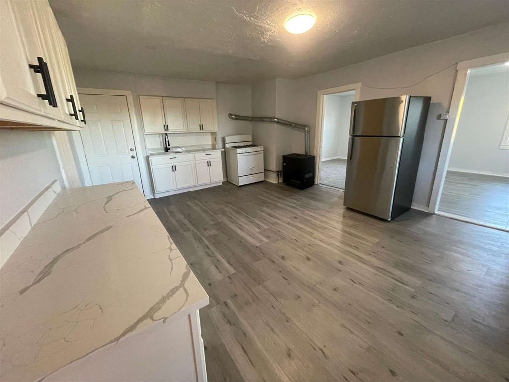573 Main Street Southbridge, MA 01550 - Photo 3 of 15 a view of a kitchen with refrigerator and wooden floor