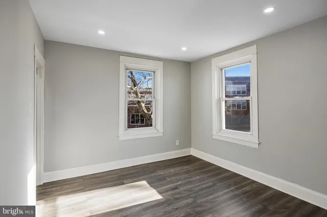 an empty room with wooden floor and windows