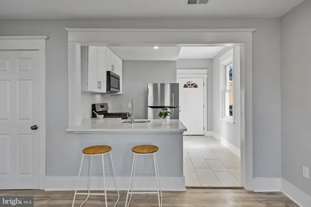 a view of a kitchen with kitchen island stainless steel appliances table chairs sink and refrigerator