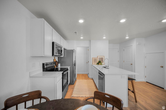 2216 Wolverine Way Washington, UT 84780 - Photo 6 of 29 Modern kitchen featuring white cabinetry, light countertops, and wood-finish flooring