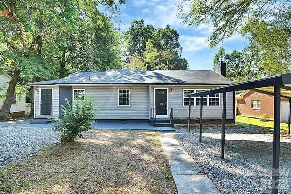 a view of a house with a yard and large tree