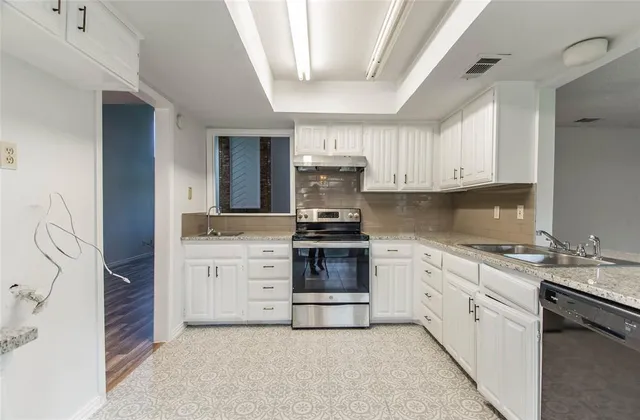 a kitchen with granite countertop white cabinets and stainless steel appliances