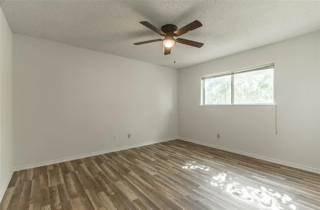 a view of a big room with wooden floor and windows