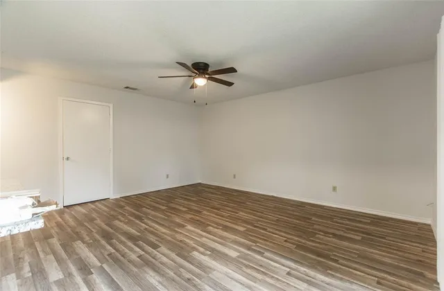 a view of a big room with wooden floor and a ceiling fan