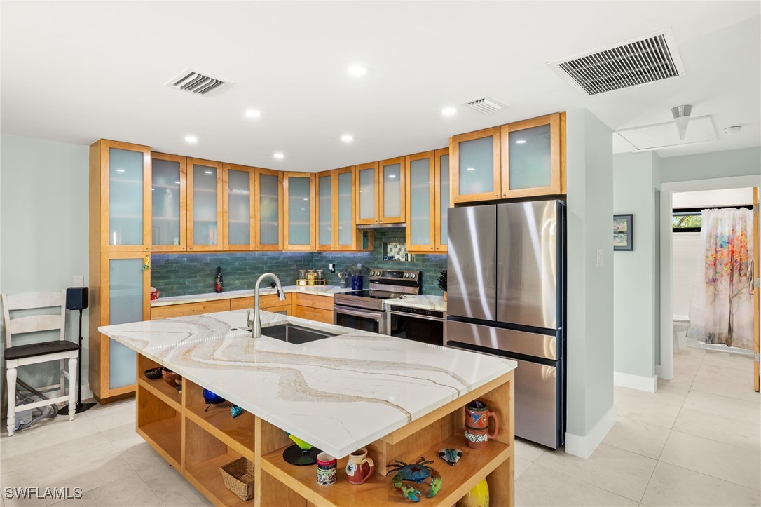 771 Rabbit Road Sanibel, FL 33957 - Photo 7 of 35 a kitchen with stainless steel appliances granite countertop a refrigerator a stove and a sink with wooden cabinets