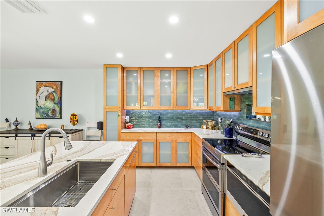 771 Rabbit Road Sanibel, FL 33957 - Photo 9 of 35 a kitchen with stainless steel appliances granite countertop a sink stove and cabinets
