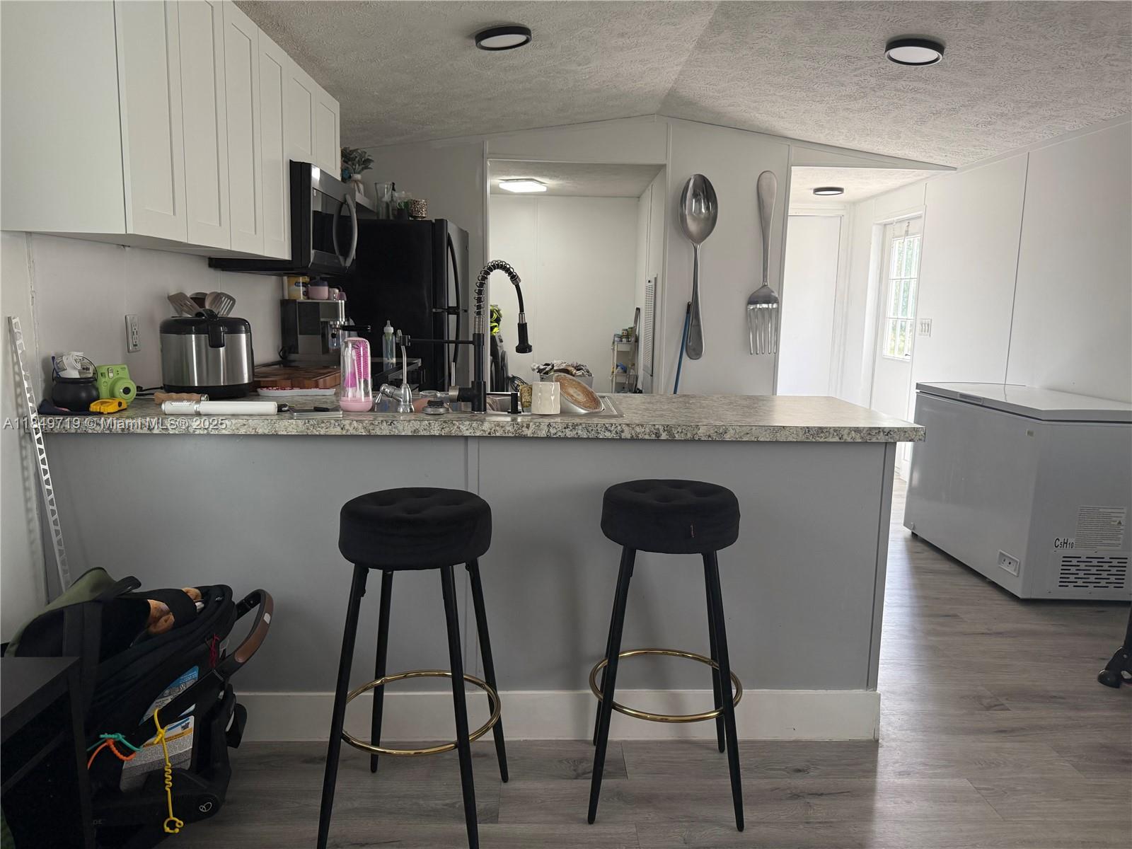 830 South Kennel Street Clewiston, FL 33440 - Photo 5 of 30 a kitchen with stainless steel appliances granite countertop a table chairs in it and wooden floors
