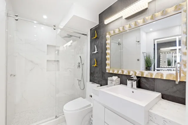 a bathroom with a sink a toilet a mirror and a shower