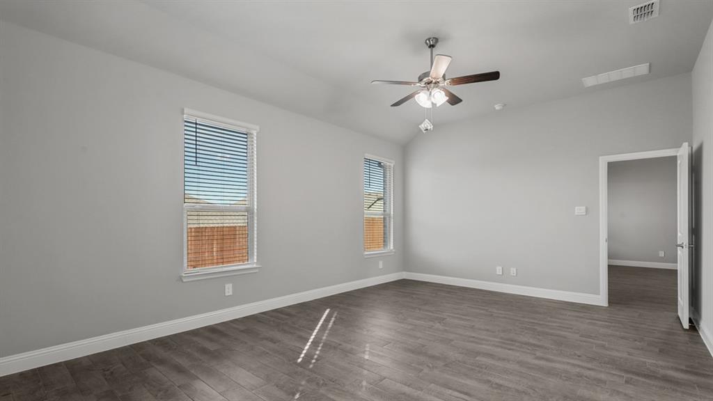11209 Treehouse Trail Justin, TX 76247 - Photo 15 of 40 an empty room with wooden floor ceiling fan and windows