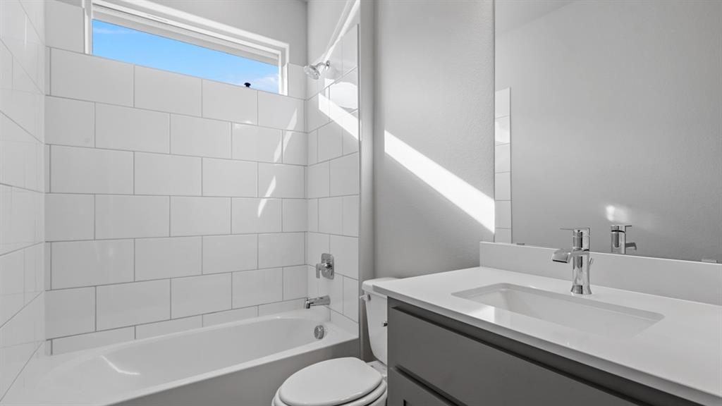 11209 Treehouse Trail Justin, TX 76247 - Photo 32 of 40 a bathroom with a granite countertop sink toilet a mirror and bathtub