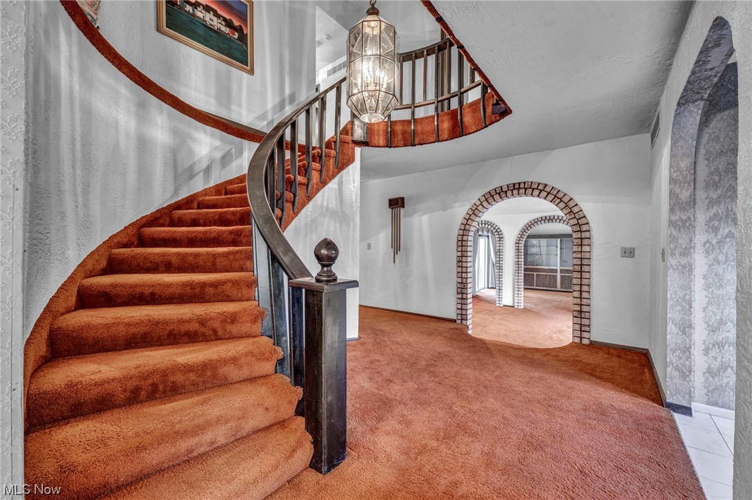 230 Crosse Road Amherst, OH 44001 - Photo 17 of 47 Staircase with a notable chandelier and light colored carpet