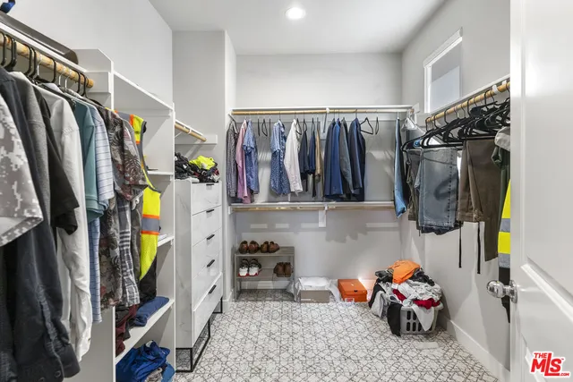 a view of walk in closet with clothes and shoes