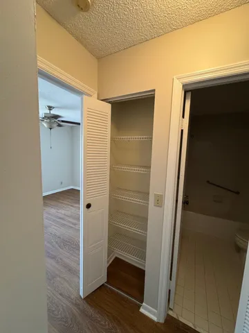 an empty room with wooden floor closet and windows