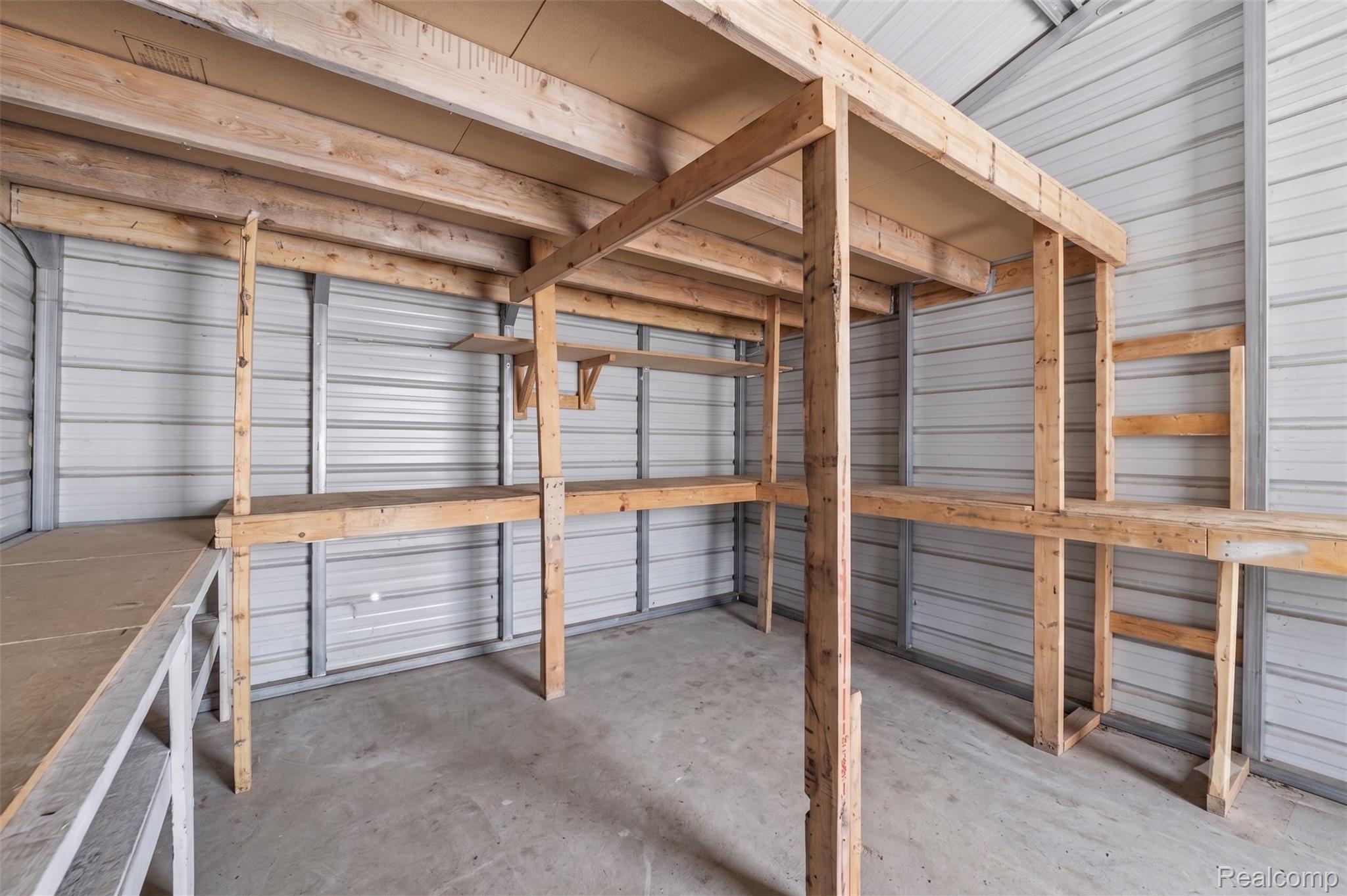 2166 South Forman Road Baldwin, MI 49304 - Photo 27 of 31 Interior storage space featuring corrugated metal walls, concrete flooring, and built-in wood shelving and work surfaces