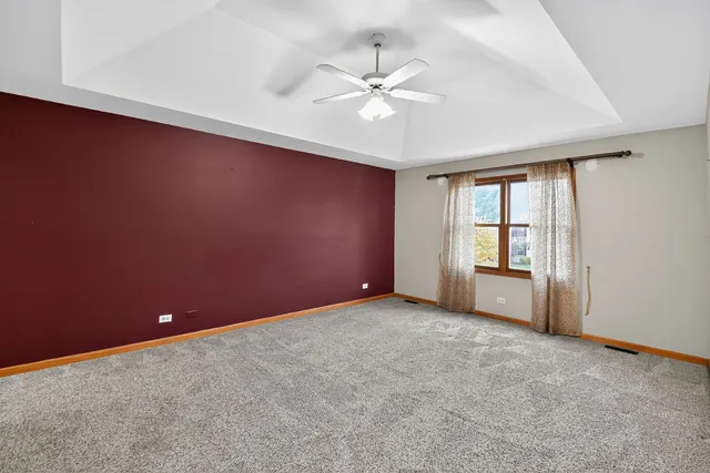 an empty room with chandelier fan and windows