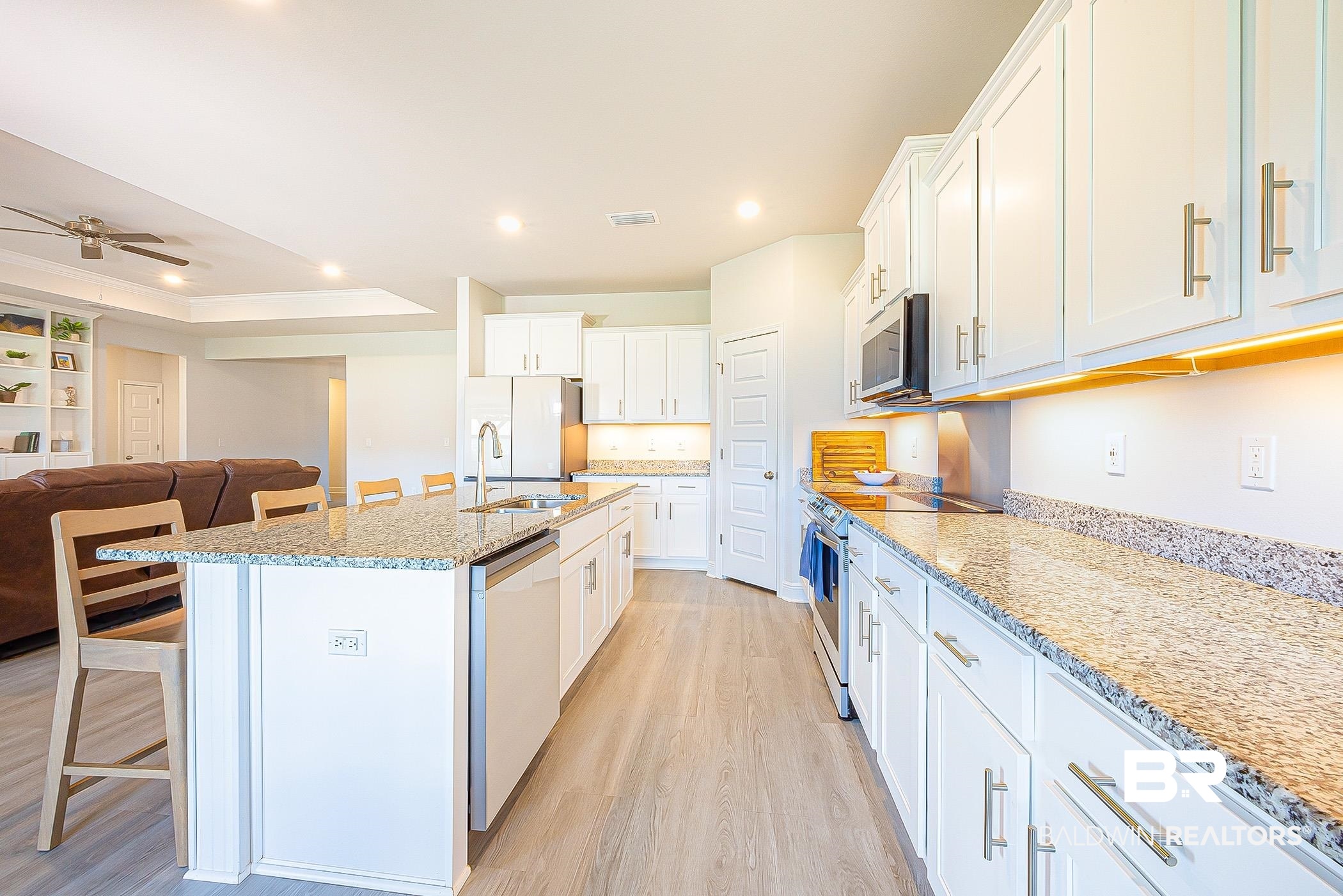 11044 Native Dancer Way Daphne, AL 36526 - Photo 13 of 67 Kitchen with white cabinets, ceiling fan, stainless steel appliances, light hardwood / wood-style floors, and a center island with sink