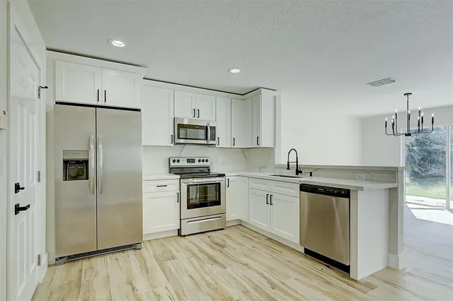 a kitchen with white cabinets stainless steel appliances and a refrigerator