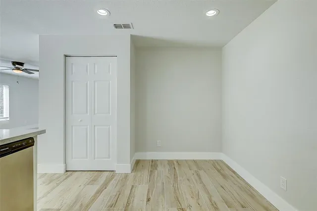 a view of an empty room with wooden floor and a sink