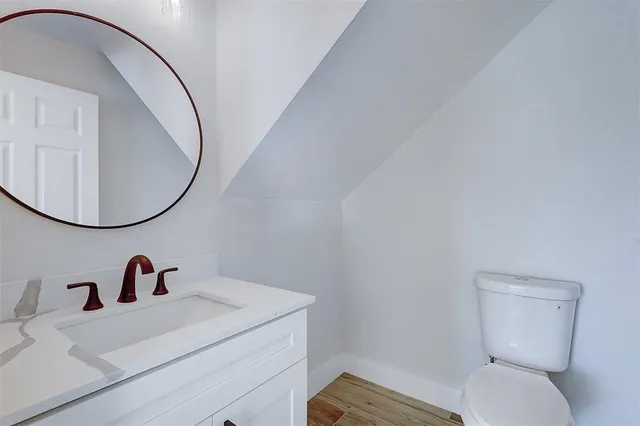 a bathroom with a toilet a sink a mirror and vanity