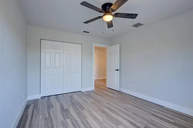 an empty room with wooden floor and a ceiling fan