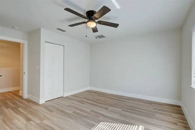 an empty room with wooden floor and ceiling fan