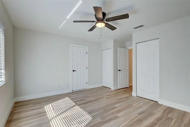 a view of a room with wooden floor and a ceiling fan