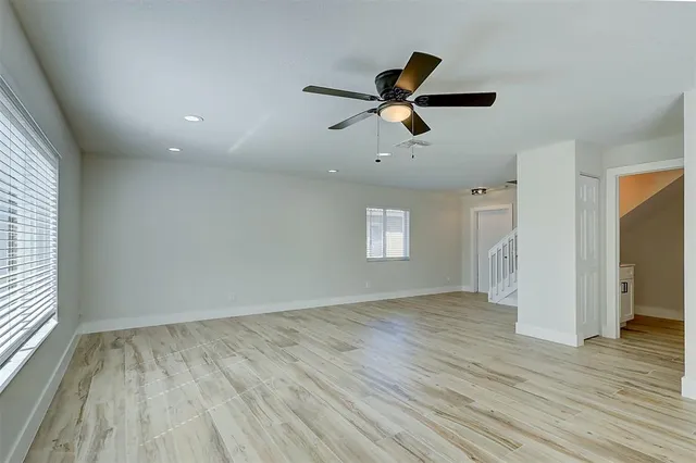 an empty room with wooden floor and windows