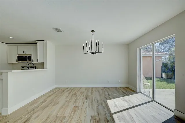 a view of a room with wooden floor a ceiling fan and windows