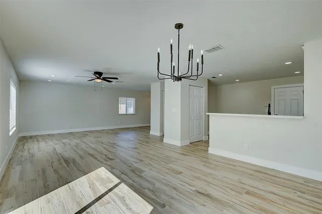 a view of empty room with wooden floor and ceiling fan